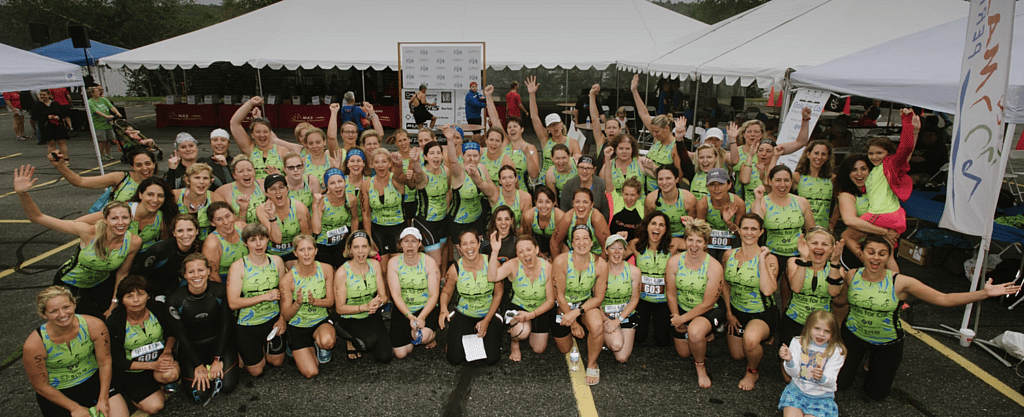 large group of triathlon runners posing together and raising hands