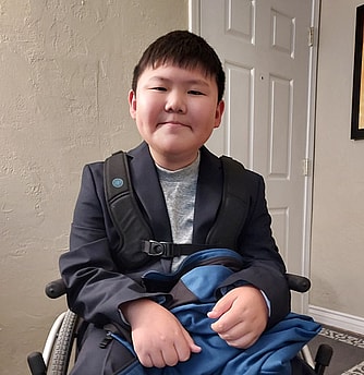 AVF recipient Timothy sits smiling in his wheelchair