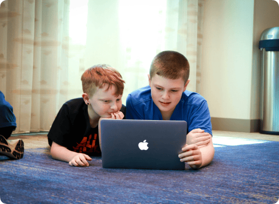 two children looking at a Macbook