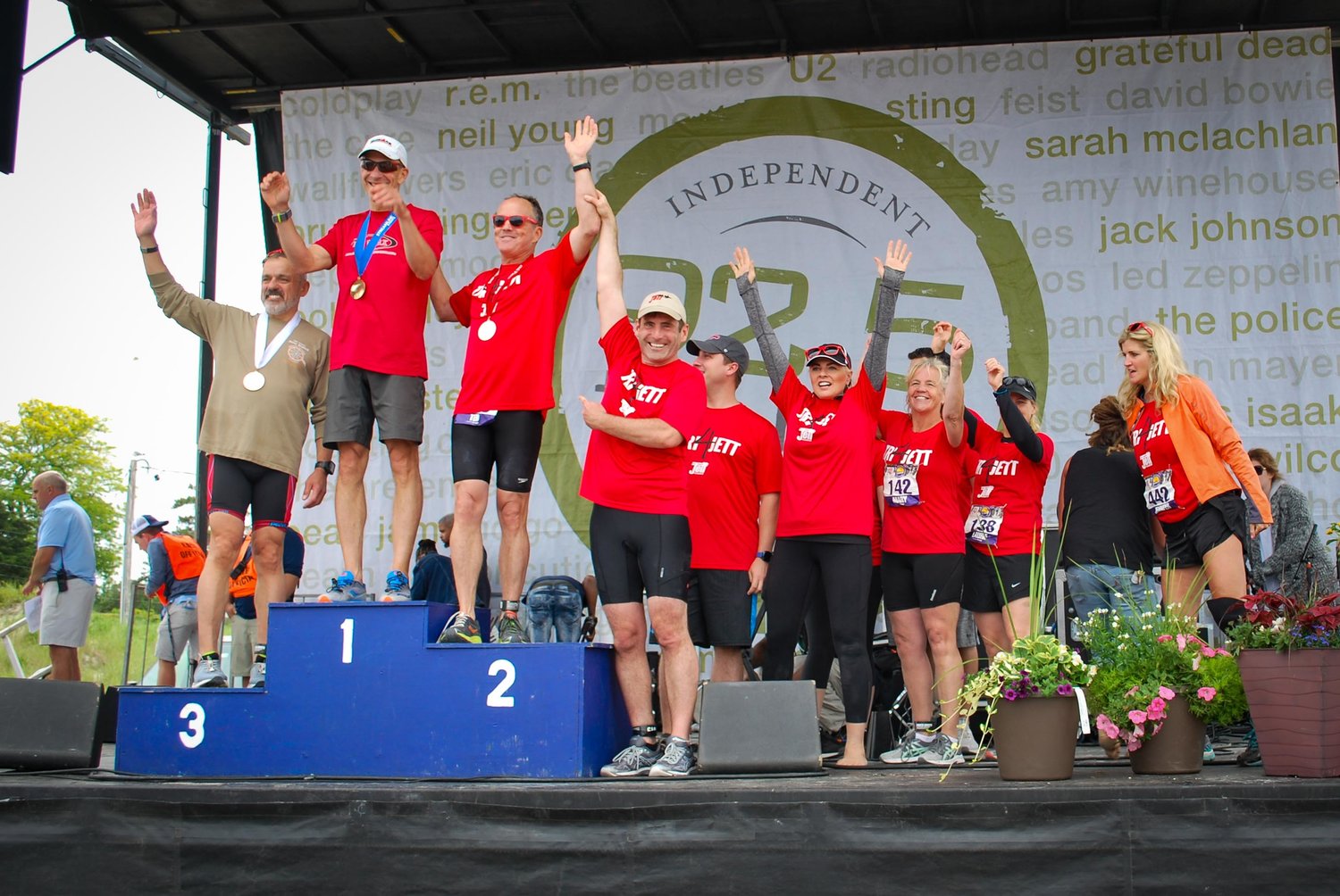 triathlon runners standing and waving on a podium