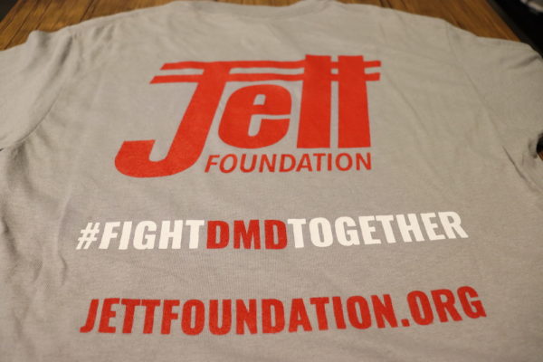 Heather gray t shirt with red Jett logo, underneath a #fightdmdtogether in red and white text and jettfoundation.org written underneath in red text